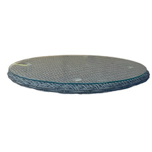 A round rotating serving platter with a glass top and a wicker base, designed for use on a dining table.