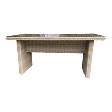 A rectangular outdoor dining table made of weatherproof wicker with a powder-coated aluminium frame and a safety glass top.