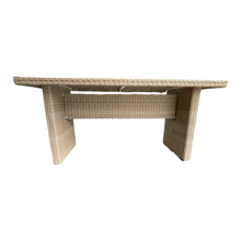 A rectangular outdoor dining table made of weatherproof wicker with a powder-coated aluminium frame and a safety glass top.