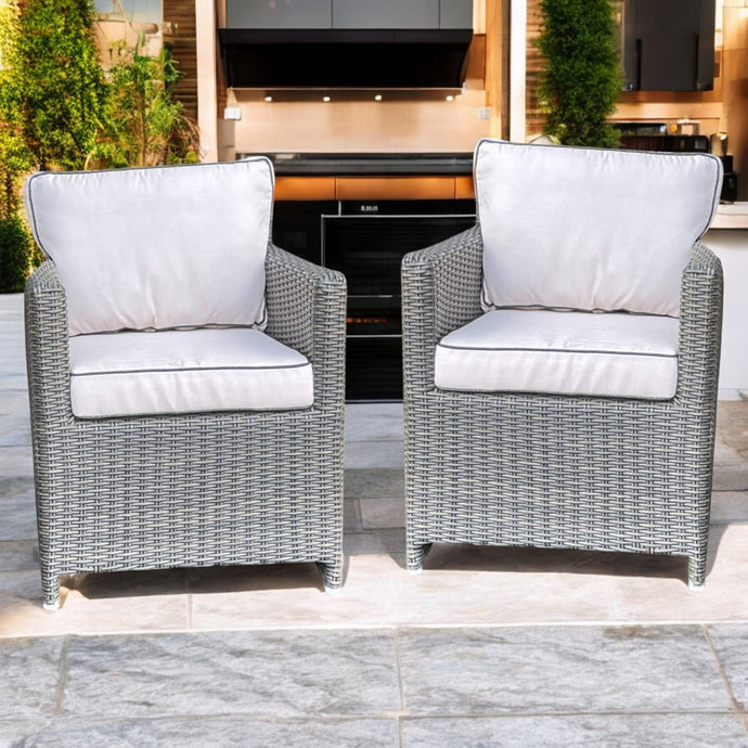 Two gray wicker armchairs with beige cushions on a patio.