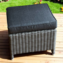 ELWOOD grey wicker ottoman with a dark cushion on a wooden deck