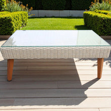 Outdoor coffee table with glass-top and wicker sides on a wooden deck - DECOR STAR