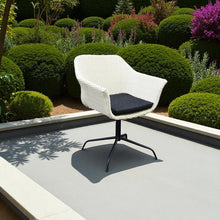 White wicker swivel chair with black cushion on a patio - DECOR STAR